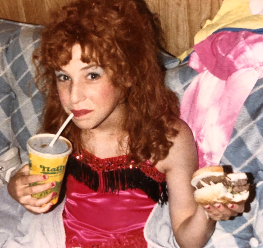 Mayim Bialik eating a Nathan's hamburger on the Beaches set